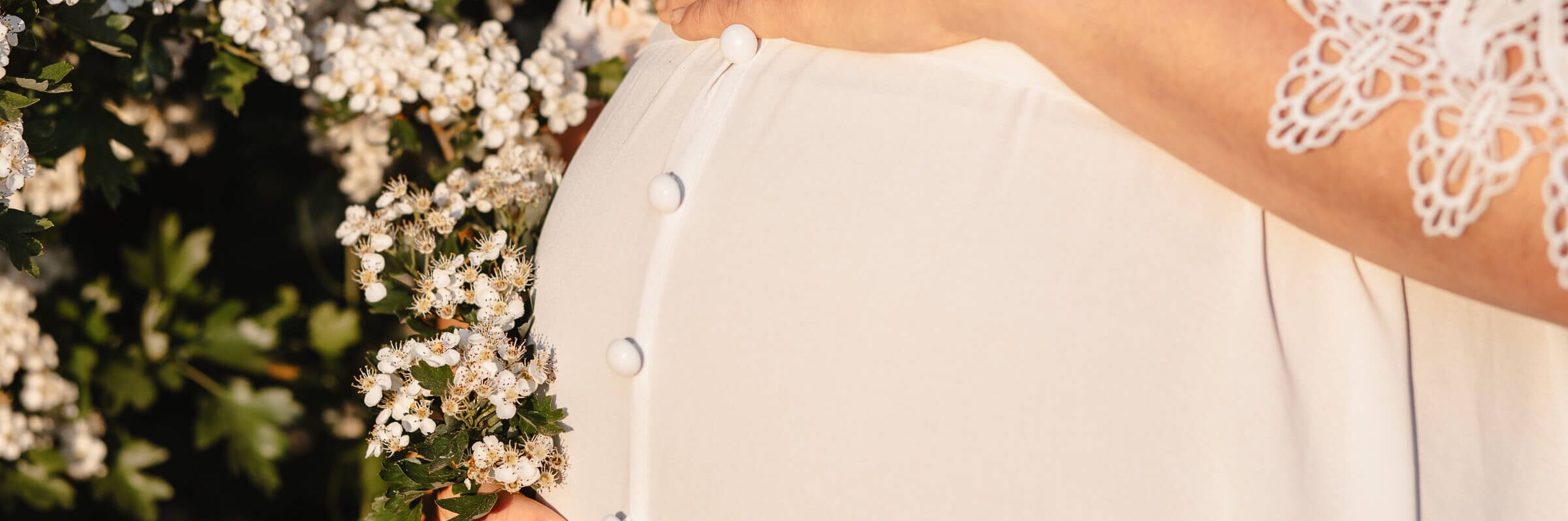 Babybauch Großaufnahme vor Blüten