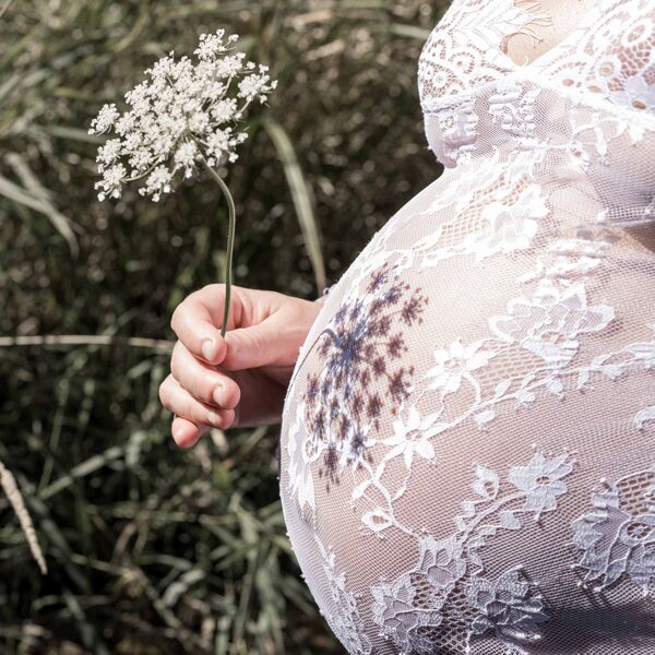 Schatten einer Blume auf dem Babybauch