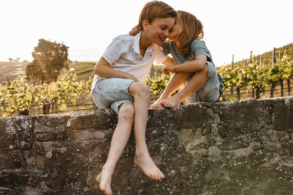 Kreative Familienfotos aus dem Nürnberger Land Geschwister küssen sich auf einer Steinmauer