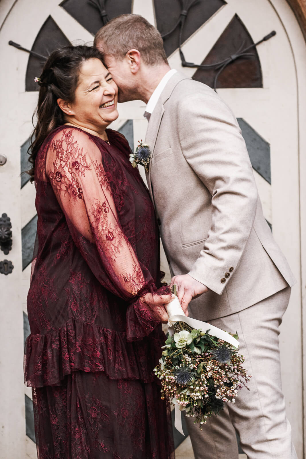 Ein Hochzeitspaar lacht vor einer Tür, eingefangen vom Hochzeitsfotograf im Nürnberger Land.